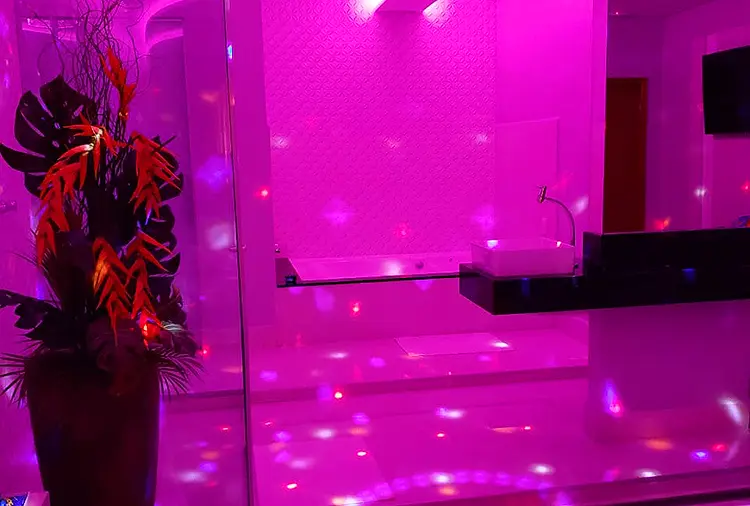 Banheira de hidromassagem sob iluminação magenta sedutora com cromoterapia na Suíte Vênus