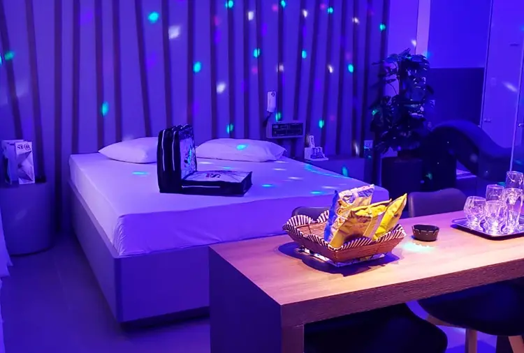 Iluminação cênica azul e mesa de jantar em ambiente aconchegante da Suíte Vênus